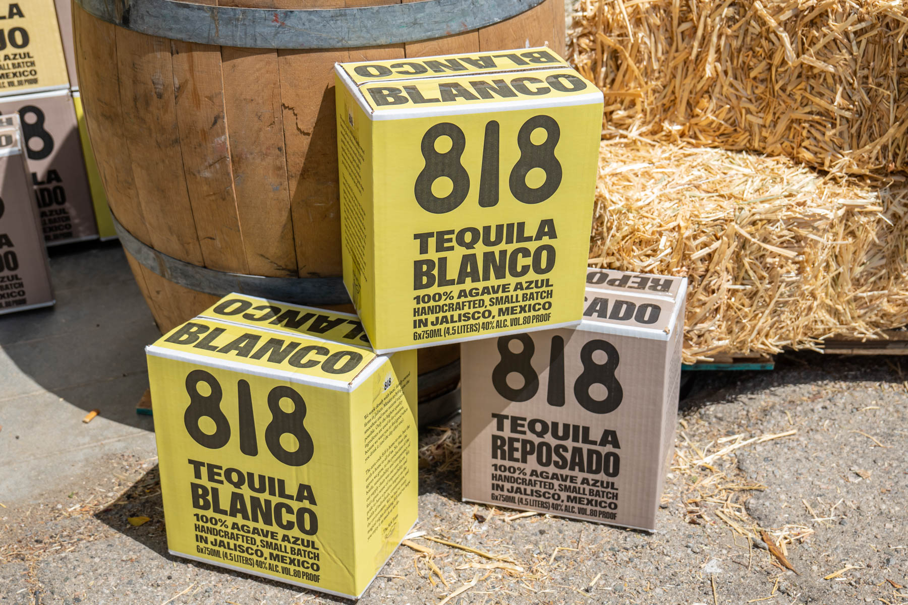 A couple of 818 Tequila boxes against a barrel and hay.
