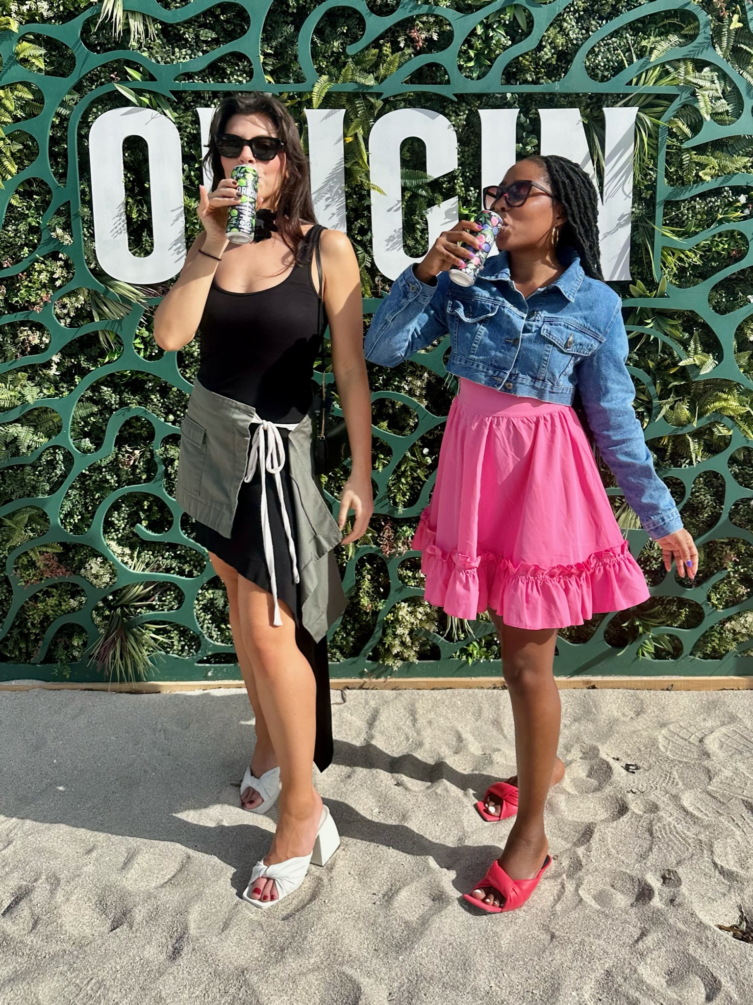 Two friends sipping Origin in front of the Origin mural.