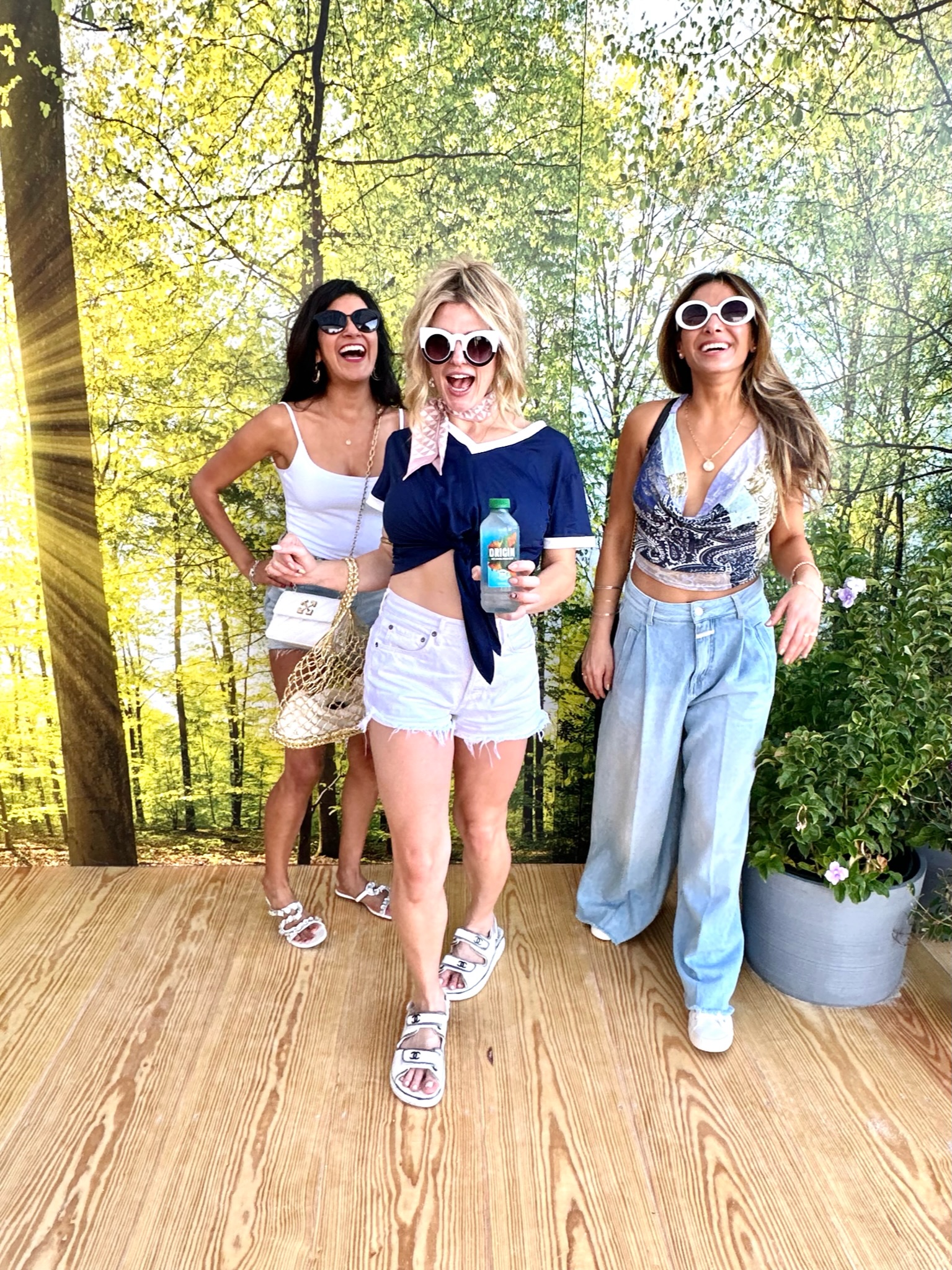 Three friends posing in front of a forest backdrop at the tasting bar.
