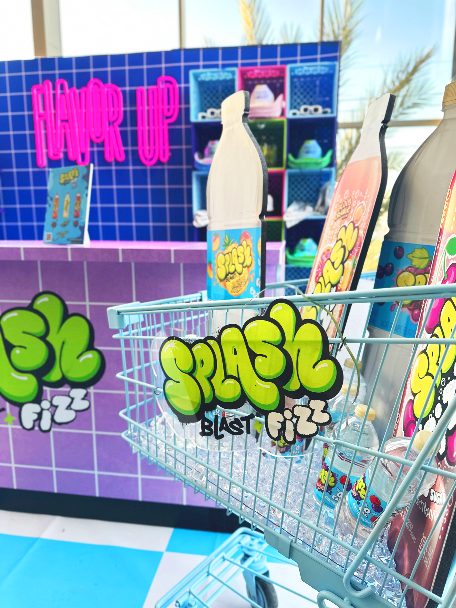 A grocery cart filled with giant cutouts of Splash Blast and Splash Fizz in front of the Funky Bodega.